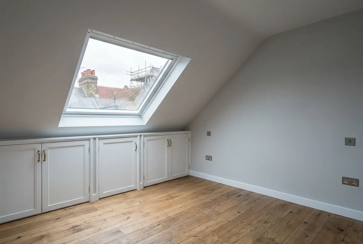 A finished loft conversion bedroom with a roof window