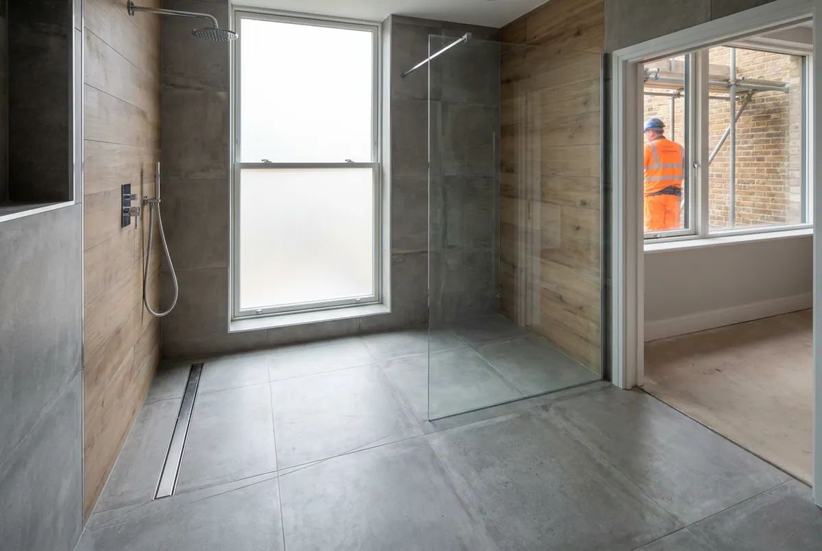 A completed wet room with a linear drain and glass screen